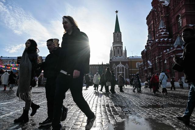 People walk near the State Historical Museum in central Moscow during the Defender of the Fatherland Day on February 23, 2026. (Photo by Hector RETAMAL / AFP)