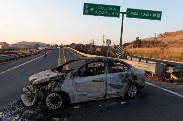 A view of a burned car, allegedly set on fire by organised crime groups in response to an operation to arrest a high-priority security target, on a highway near Acatlan de Juarez, Jalisco state, Mexico on February 22, 2026. The Mexican army announced that it had killed powerful drug lord Nemesio "El Mencho" Oseguera in an operation that sparked a wave of violence in various parts of the country on February 22, 2026. Gunmen retaliating for the raid blocked more than 20 roads in western Jalisco state, which includes Tapalpa, with burning cars and trucks. The violence spread to other states as well. (Photo by Ulises Ruiz / AFP)
