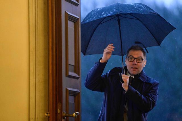 TOPSHOT - Oleksii Makeiev, Ukraine's ambassador to Germany, shelters from the rain under an umbrella as he arrives to meet with German President Frank-Walter Steinmeier (not in picture) for an event marking the 4th anniversary of Russia's full-scale invasion of Ukraine at the presidential Bellevue Palace in Berlin, on February 23, 2026. (Photo by John MACDOUGALL / AFP)