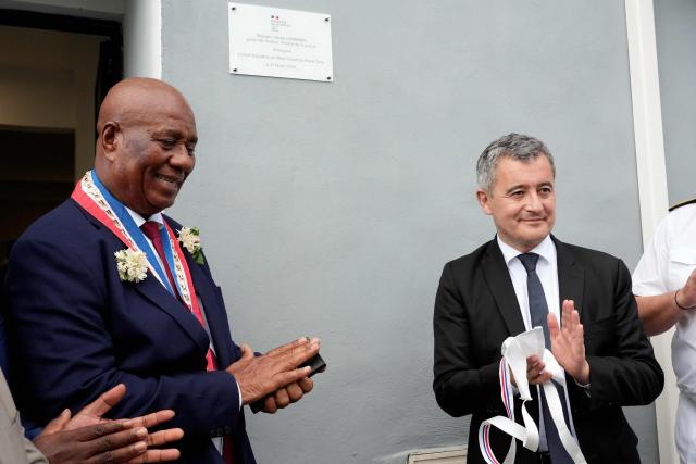 French Minister of Justice, Gerald Darmanin (R), and Pamandzi Mayor, Madi Madi Souf (L), applaud after unveiling a plaque to inaugurate the new open-environment educational unit, in Pamandzi, on the French Indian Ocean territory of Mayotte, on February 23, 2026. (Photo by Marine GACHET / AFP)