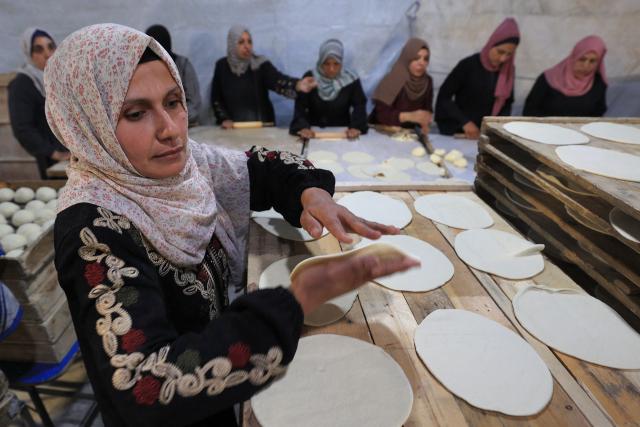 Palestinian women prepare bread for distribution to families in need at the Bureij camp for the displaced during the Muslim holy fasting month of Ramadan, on February 23, 2026. (Photo by Eyad Baba / AFP)