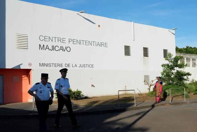 A police officer and an gendarme walk in front of the Majicavo Correctional Center in the village of Majicavo Lamir, in the township of Koungou, on the French Indian Ocean territory of Mayotte, on February 23, 2026. (Photo by Marine GACHET / AFP)