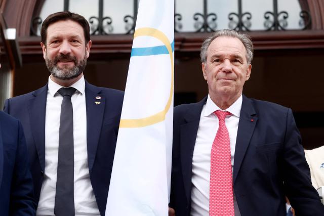 French president of the Rhone-Alpes region Fabrice Pannekoucke and Provence-Alpes-Côte d'Azur region president Renaud Muselier (R) pose with the Olympic flag during a ceremony of arrival of the Olympic flag marking the handover from Milano Cortina 2026 to French Alps 2030 Winter Olympic Games, in the French Alps in Albertville, south-eastern France on February 23, 2026. (Photo by Alex MARTIN / AFP)