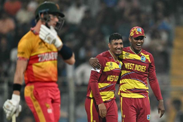 West Indies' Gudakesh Motie (C) celebrates after taking the wicket of Zimbabwe's Tony Munyonga (L) during the 2026 ICC Men's T20 Cricket World Cup Super Eights match between West Indies and Zimbabwe at the Wankhede Stadium in Mumbai on February 23, 2026. (Photo by Punit PARANJPE / AFP)