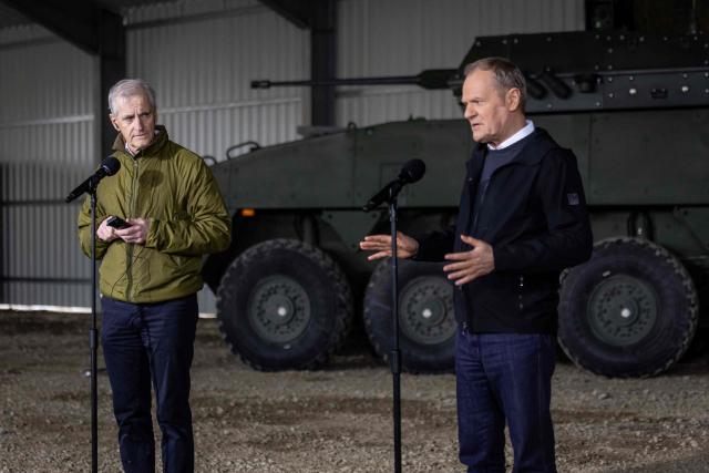 Norway's Prime Minister Jonas Gahr Store (L) listens as Poland's Prime Minister Donald Tusk speaks during press conference on February 23, 2026, in Camp Jomsborg - Norwegian Army training camp located in Lipa, south-eastern Poland, established to train Ukrainian soldiers. (Photo by Wojtek RADWANSKI / AFP)