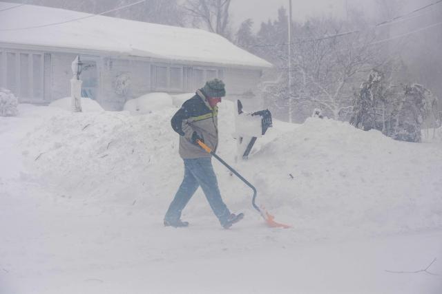A person uses a shovel to clear their property in Norwell, Massachusetts on February 23, 2026. Tens of millions of Americans from the US capital Washington to the northern state of Maine prepared for up to two feet (60 centimeters) of snow forecast in some areas. The National Weather Service (NWS) said blizzard conditions would "quickly materialize" from Maryland up to southeastern New England, making travel "extremely treacherous." (Photo by Joseph Prezioso / AFP)