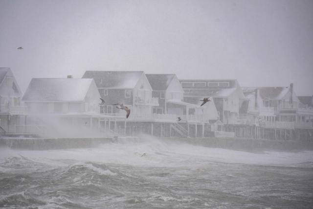 High waves pound houses on the shoreline in Scituate, Massachusetts on February 23, 2026. Tens of millions of Americans from the US capital Washington to the northern state of Maine prepared for up to two feet (60 centimeters) of snow forecast in some areas. The National Weather Service (NWS) said blizzard conditions would "quickly materialize" from Maryland up to southeastern New England, making travel "extremely treacherous." (Photo by Joseph Prezioso / AFP)