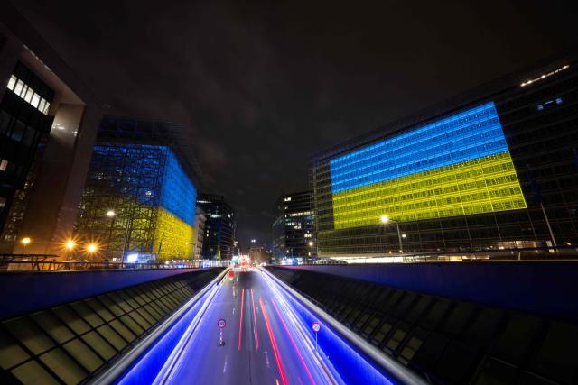 This photograph shows a general view of the European Union Council building (L) and the European Union Commission building illuminated and bearing the colours of Ukraine's national flag, following a ceremony to mark the fourth anniversary of Russia's war of aggression against Ukraine in Brussels on February 23, 2026. The EU's foreign policy chief expressed on February 23, 2026 regret that the bloc failed to unanimously agree new sanctions on Russia for the fourth anniversary of the Ukraine war, after Hungary vetoed the move. (Photo by JOHN THYS / AFP)