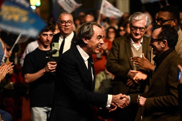 Candidate for the upcoming municipal election in Bordeaux Philippe Dessertine (C) shakes hands with a supporter as he arrives for an electoral meeting at a theatre in Bordeaux, south-western France, on February 23, 2026. (Photo by Christophe ARCHAMBAULT / AFP)