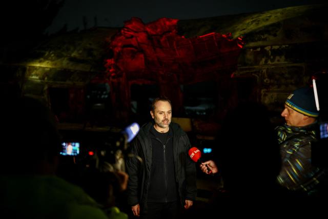 Head of Ukranian Railways Oleksandr Pertsovskyi speaks to media next to a Ukrainian railway carriage that was attacked by a Russian drone on January 27, 2026 near Kharkiv in eastern Ukraine killing six people, on display at the Kyiv central train station on February 23, 2026, ahead of the fourth anniversary of Russia's invasion of Ukraine. Russia launched its full-scale invasion of Ukraine on February 24, 2022, unleashing the deadliest war in Europe since World War II. (Photo by HENRY NICHOLLS / AFP)