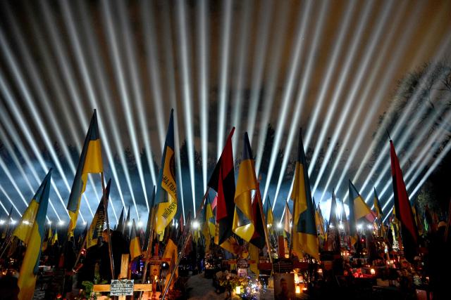 A symbolic illumination entitled "Rays of Memory" is projected over the graves of Ukrainian soldiers who died in the war with Russia at the Lychakiv Military Cemetery in Lviv, on February 23, 2026, ahead of the fourth anniversary of Russia's invasion of Ukraine. Russia launched its full-scale invasion of Ukraine on February 24, 2022, unleashing the deadliest war in Europe since World War II. (Photo by YURIY DYACHYSHYN / AFP)