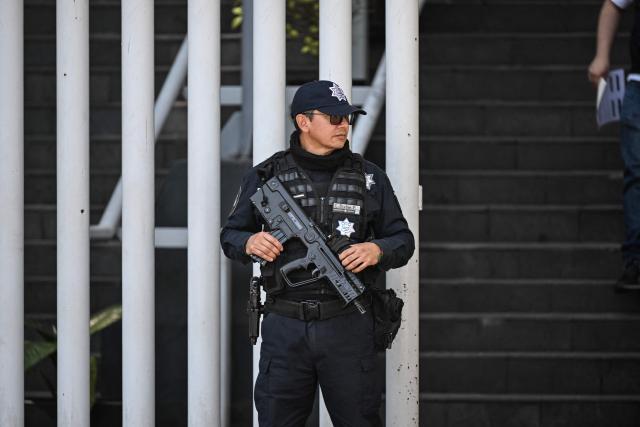 A member of Federal security stands guard around the headquarters of the Specialized Prosecutor's Office for Organized Crime (FEMDO) in Mexico City on February 23, 2026. Mexico has deployed 10,000 troops to quell clashes sparked by the killing of the country's most wanted drug lord, which have left dozens dead, officials said on February 23. Nemesio "El Mencho" Oseguera, leader of the Jalisco New Generation Cartel (CJNG), was wounded on February 22 in a shootout with soldiers in the town of Tapalpa in Jalisco state and died while being flown to Mexico City, the army said. (Photo by Yuri CORTEZ / AFP)