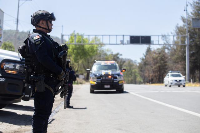 Police officers conduct a security checkpoint on the MoreliaPatzcuaro Highway to prevent vehicle fires and road blockades in Michoacan state, Mexico, on February 23, 2026. Mexico has deployed 10,000 troops to quell clashes sparked by the killing of the country's most wanted drug lord, which have left dozens dead, officials said on February 23. Nemesio "El Mencho" Oseguera, leader of the Jalisco New Generation Cartel (CJNG), was wounded on February 22 in a shootout with soldiers in the town of Tapalpa in Jalisco state and died while being flown to Mexico City, the army said. (Photo by Enrique Castro / AFP)