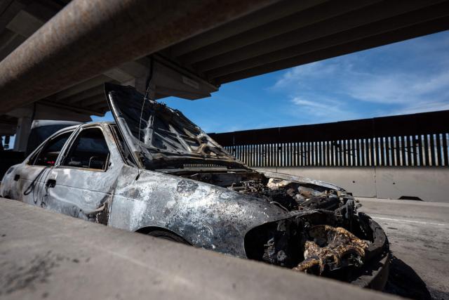 A burned car is seen on International Avenue, allegedly set on fire by organized crime groups, on the Mexican side of the US-Mexico border in Tijuana, Baja California State, Mexico on February 23, 2026. Mexico has deployed 10,000 troops to quell clashes sparked by the killing of the country's most-wanted drug lord, Nemesio "El Mencho" Oseguera, leader of the Jalisco New Generation Cartel (CJNG), that have claimed dozens of lives, officials said on February 23. News of his death triggered spasms of violence, with cartel members blocking roads in 20 states and torching vehicles and businesses. (Photo by Guillermo ARIAS / AFP)
