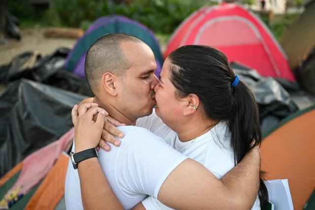 Venezuelan prisoner Carlos Jose Rodriguez (L) kisses his wife after his release from El Rodeo I prison in Guatire, Miranda state, Venezuela on February 23, 2026. At least 30 political prisoners were released from a prison on the outskirts of Caracas on the afternoon of February 23, 2026, under a historic amnesty law enacted in Venezuela under pressure from Washington, AFP journalists reported. (Photo by Federico PARRA / AFP)