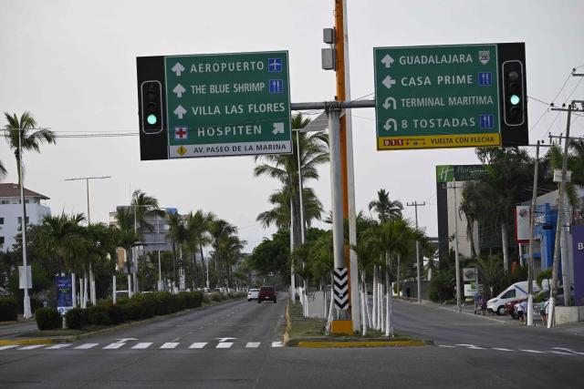 Vehicles drive along an almost empty street in Puerto Vallarta, Jalisco state, Mexico, on February 23, 2026. Mexico has deployed 10,000 troops to quell clashes sparked by the killing of the country's most wanted drug lord, which have left dozens dead, officials said on February 23. Nemesio "El Mencho" Oseguera, leader of the Jalisco New Generation Cartel (CJNG), was wounded on February 22 in a shootout with soldiers in the town of Tapalpa in Jalisco state and died while being flown to Mexico City, the army said. (Photo by Alfredo ESTRELLA / AFP)