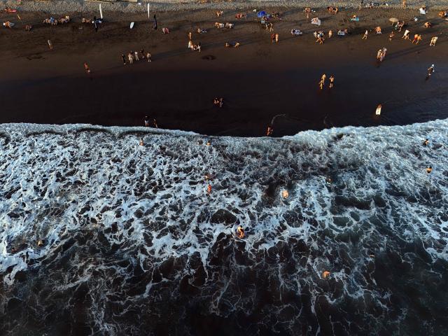 This aerial view shows El Tunco beach, in La Libertad, El Salvador, on February 13, 2026. Amid picture-perfect waves and sunsets, foreign tourists enjoy the Salvadoran beach of El Tunco, once plagued by gang violence. They are full of praise for President Nayib Bukele, even though they admit that innocent people may have been caught up in his crackdown. (Photo by Marvin RECINOS / AFP)