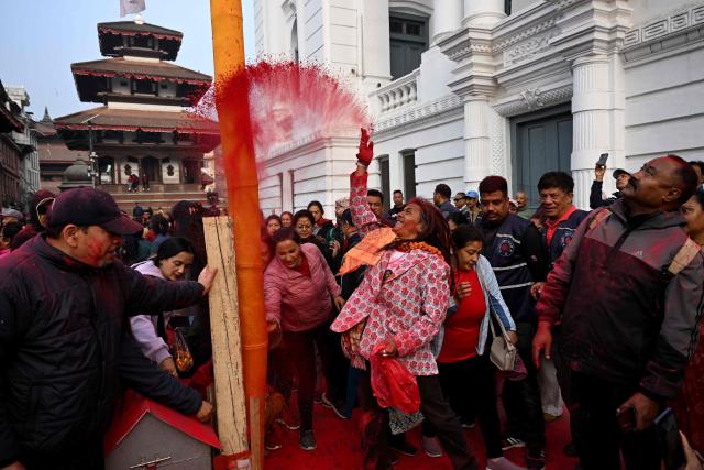 Devotees throw coloured powder towards a traditional sacred bamboo pole "Chir", 
fringed with strips of cloth representing good luck charms at the Basantapur Durbar Square in Kathmandu on February 24, 2026 to mark the beginning of Holi festival celebrations. (Photo by PRAKASH MATHEMA / AFP)