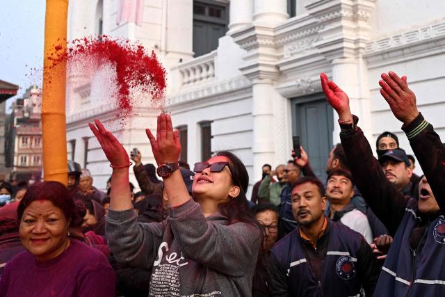 Devotees throw coloured powder towards a traditional sacred bamboo pole "Chir", 
fringed with strips of cloth representing good luck charms at the Basantapur Durbar Square in Kathmandu on February 24, 2026 to mark the beginning of Holi festival celebrations. (Photo by PRAKASH MATHEMA / AFP)