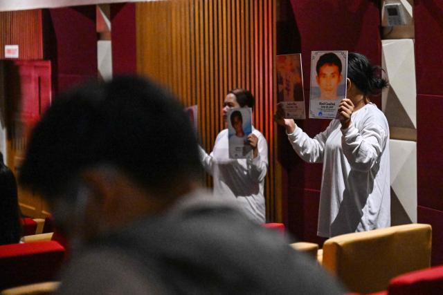 Relatives of the victims of extrajudicial killings of former Philippine president Rodrigo Duterte's drug war, hold their victims’ portraits as they perform a theatre play called “Teatro Paghilom”, a holistic program that aims to help the widows and orphans of extrajudicial killings victims rebuild and re-create their lives, at a university in Manila on February 24, 2026. The International Criminal Court (ICC) opened hearings on February 23, to decide whether former Philippine president Rodrigo Duterte should stand trial for crimes against humanity linked to his deadly anti-drug crackdown. (Photo by Jam STA ROSA / AFP)