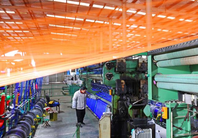 A woman works on a netting production line in Lianyungang, eastern China's Jiangsu province on February 24, 2026. (Photo by CN-STR / AFP) / China OUT