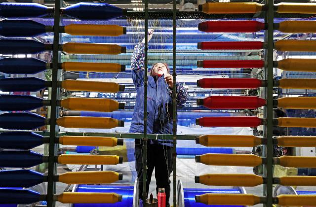 A woman works on a netting production line in Lianyungang, eastern China's Jiangsu province on February 24, 2026. (Photo by CN-STR / AFP) / China OUT