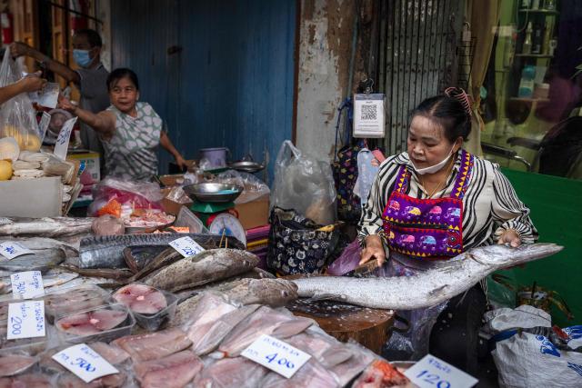 A fish vendor scales a fish at Trok Mor Morning Market in Bangkok on February 24, 2026. (Photo by chanakarn laosarakham / AFP)