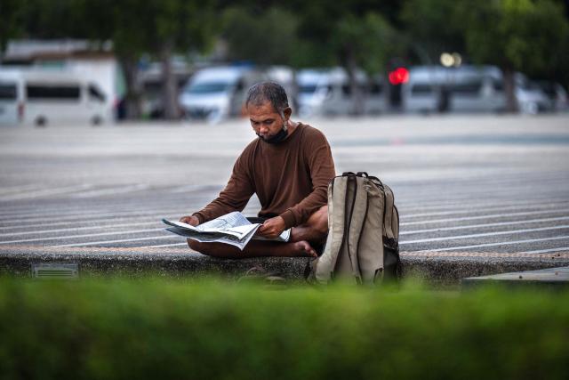 A man reads a newspaper in Bangkok on February 24, 2026. (Photo by chanakarn laosarakham / AFP)
