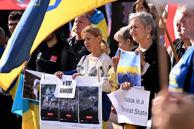 Members of the local Ukrainian community hold up placards during a rally to mark the fourth anniversary of the Russia-Ukraine war, in Melbourne on February 24, 2026. (Photo by William WEST / AFP)