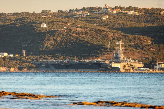 US aircraft carrier USS Gerald Ford is pictured docked at Souda Bay in the Greek Mediterranean island of Crete, on February 24, 2026. Upon military orders by US President Donald Trump, the world's largest vessel is on its way to the Middle East to join 13 more warships stationed in the region: the aircraft carrier USS Abraham Lincoln, which arrived late last month, nine destroyers and three frigates. (Photo by Costas METAXAKIS / AFP)