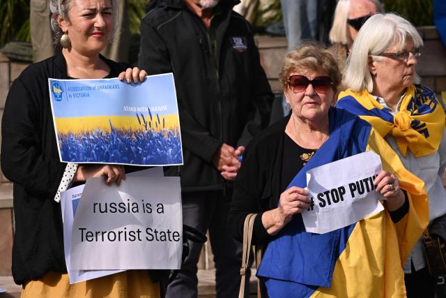 Members of the local Ukrainian community hold up placards during a rally to mark the fourth anniversary of the Russia-Ukraine war, in Melbourne on February 24, 2026. (Photo by William WEST / AFP)