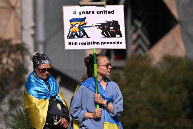 Members of the local Ukrainian community hold up placards during a rally to mark the fourth anniversary of the Russia-Ukraine war, in Melbourne on February 24, 2026. (Photo by William WEST / AFP)
