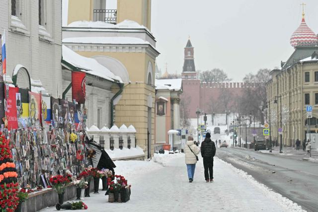 People walk past a memorial for the fallen Russian soldiers, including Russia's Wagner paramilitary group fighters, on a street in Moscow on February 24, 2026, on the fourth anniversary of the ongoing Russia-Ukraine conflict. (Photo by HECTOR RETAMAL / AFP)