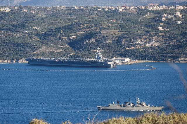 US aircraft carrier USS Gerald Ford (L) is pictured docked at Souda Bay in the Greek Mediterranean island of Crete, on February 24, 2026. Upon military orders by US President Donald Trump, the world's largest vessel is on its way to the Middle East to join 13 more warships stationed in the region: the aircraft carrier USS Abraham Lincoln, which arrived late last month, nine destroyers and three frigates. (Photo by Costas METAXAKIS / AFP)