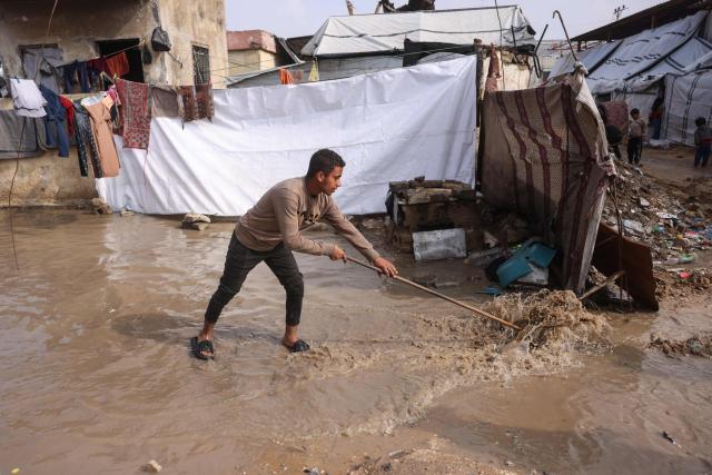 A man tries to divert the rain at a makeshift camp sheltering displaced Palestinians after heavy rains in Khan Yunis, in the southern Gaza Strip, on February 24, 2026. Under the first phase of a US-sponsored ceasefire in Gaza intended to halt two years of war, the Israeli army withdrew to positions behind a so-called Yellow Line, but still controls over half of the territory. Nearly all of Gaza's 2.2 million residents were displaced at least once during the war sparked by Palestinian Islamist group Hamas's unprecedented October 7 attack. (Photo by Bashar Taleb / AFP)