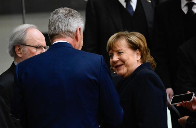 Former German Chancellor Angela Merkel (R) talks with former president of the Bundestag Wolfgang Thierse (L) and former German President Christian Wulff as they attend a commemoration ceremony for late former Bundestag President Rita Suessmuth at the Bundestag (lower house of parliament) in Berlin, on February 24, 2026. (Photo by John MACDOUGALL / AFP)