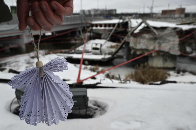 A person holds symbolyc paper white angel, standing on a destroyed bridge in Irpin, northwest of Kyiv, during a memorial ceremony on February 24, 2026, on the fourth anniversary of Russia's invasion of Ukraine. In 2022, many residents of Irpin, which was turned into a battlefield early in Russia's full-scale invasion, passed under the destroyed bridge in an attempt escape towards Kyiv. (Photo by Genya SAVILOV / AFP)