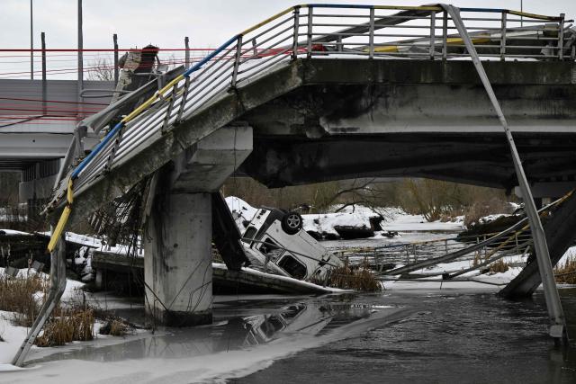 This photograph shows a destroyed bridge in Irpin, northwest of Kyiv, during a memorial ceremony on February 24, 2026, on the fourth anniversary of Russia's invasion of Ukraine. In 2022, many residents of Irpin, which was turned into a battlefield early in Russia's full-scale invasion, passed under the destroyed bridge in an attempt escape towards Kyiv. (Photo by Genya SAVILOV / AFP)