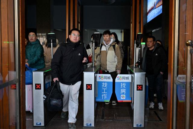 People arrive from their hometown after spring festival holidays at the Beijing station in Beijing on February 24, 2026. (Photo by Adek BERRY / AFP)