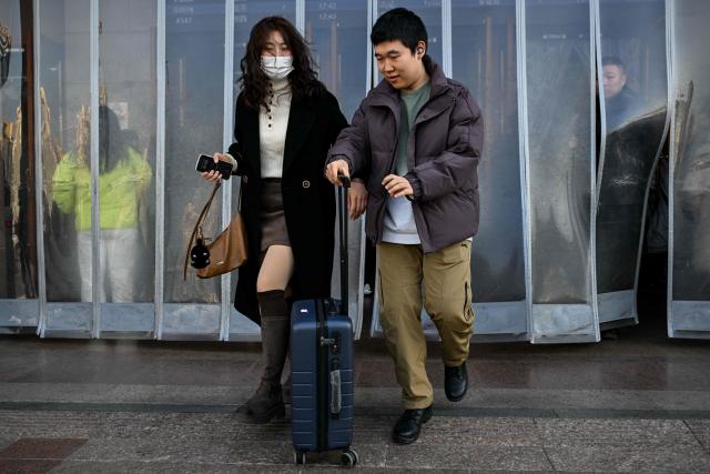 People arrive from their hometown after the spring festival holidays at the Beijing station in Beijing on February 24, 2026. (Photo by Adek BERRY / AFP)