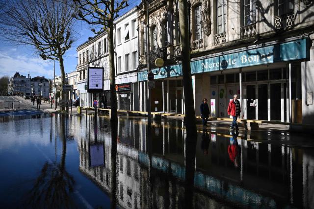 Local residents walks through a flooded street following severe flooding caused by Storm Nils in Saintes, south-western France, on February 24, 2026. (Photo by Christophe ARCHAMBAULT / AFP)