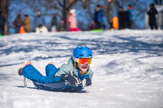 Children sled down the snow covered Flagstaff Hill in Boston Common in Boston, Massachusetts on February 24, 2026. More than 40 million people were under weather warnings in the northeastern United States, as a winter storm dumped shin-deep snow and officials enforced travel bans and school closures in several cities. The so-called "Nor'easter" pummeled the region, disrupting flights and leaving hundreds of thousands of homes and businesses without power. (Photo by Joseph Prezioso / AFP)