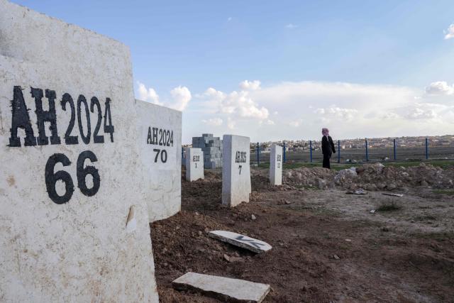 A man walks amid tombstones of unidentified individuals at the Al-Hol camp cemetery in the northeastern Hasakeh governorate on February 24, 2026. Syrian authorities have closed Al-Hol camp, which long housed relatives of suspected Islamic State group fighters, after emptying the formerly Kurdish-controlled facility, a camp official told AFP on Sunday (Photo by Bakr ALKASEM / AFP)