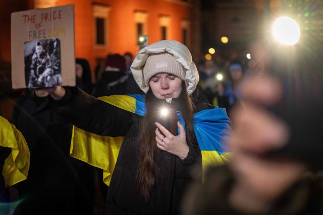 A woman holds a portrait of a fallen ukrainian soldier with an insription reading "The Price for Freedom" as she take part in rally in support of Ukraine to mark 4th anniversary of the Russian full scale invasion on Ukraine  on February 24, 2026 in front of Royal Castle, in Warsaw's Old Town. (Photo by Wojtek RADWANSKI / AFP)