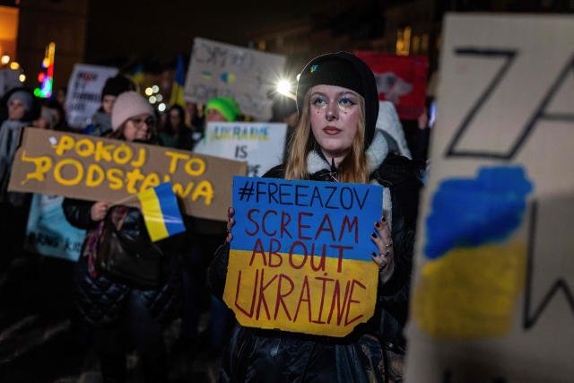 Participants hold banners reading "Peace is the foundation" and "#FreeAzov Screem About Ukraine" during the rally in support of Ukraine to mark 4th anniversary of the Russian full scale invasion on Ukraine  on February 24, 2026 in front of Royal Castle, in Warsaw's Old Town. (Photo by Wojtek RADWANSKI / AFP)