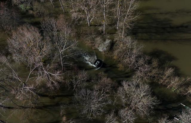 This aerial picture shows a French gendarmerie 4x4 vehicle transporting residents making its way on a flooded road from the flood-isolated village of Courcoury towards neighboring Courpignac on February 24, 2026, as the Charente-Maritime commune in south-western France remains surrounded by floodwaters following storm Nils. (Photo by Christophe ARCHAMBAULT / AFP)