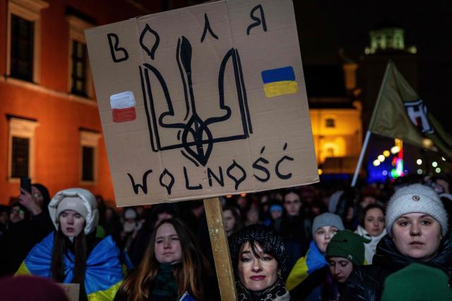 A woman holds a banner reading "Freedom" as she takes part in rally in support of Ukraine to mark 4th anniversary of the Russian full scale invasion on Ukraine  on February 24, 2026 in front of Royal Castle, in Warsaw's Old Town. (Photo by Wojtek RADWANSKI / AFP)