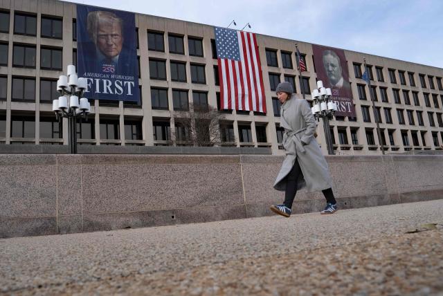 A person walks by a banner depicting US President Donald Trump on the face of the Labor Department building near the US Capitol ahead of Trump's State of the Union speech in Washington, DC, on February 24, 2026. (Photo by Ken CEDENO / AFP)