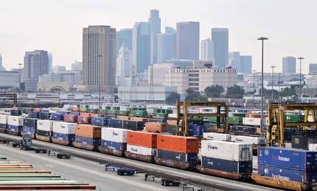The downtown Los Angeles skyline is seen behind shipping containers at the LATC-Union Pacific Los Angeles Transportation Center rail yard on February 24, 2026 in Los Angeles, California. Fresh US tariffs on imported goods came into effect Tuesday, as President Donald Trump moved to rebuild his trade agenda after the Supreme Court ruled against a swath of his global duties. The new tariffs, set at 10 percent initially, were justified as a means of dealing with "large and serious United States balance-of-payments deficits," according to a White House order on Friday. (Photo by Frederic J. BROWN / AFP)