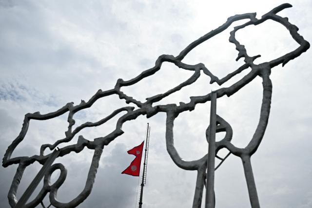 (FILES) Nepal's national flag flying at half-mast is seen through a structure built in the shape of country's map, in Kathmandu on September 17, 2025. Overseas Nepali workers bankroll their families and buttress the economy, making them a key constituency in elections next week -- but they cannot vote themselves. (Photo by Arun SANKAR / AFP)